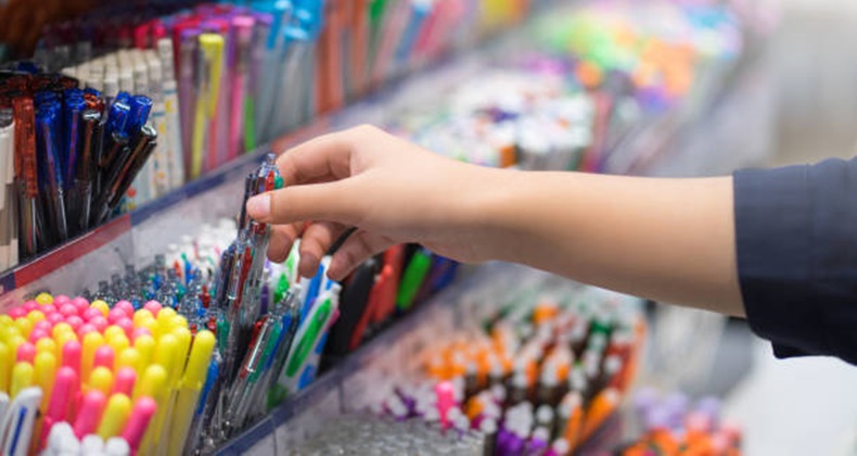 Close up hands choosing school stationery in the supermarket.