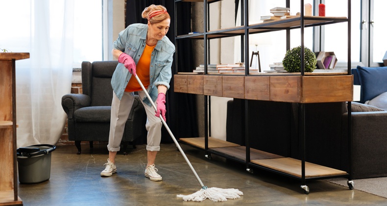 Active fit adult woman in bright outfit meticulously washing floor